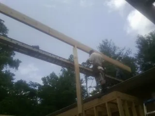 Carpenter setting a ridge beam over a new addition frame — Ice Dam Removal by Roofing Brothers in Erieville