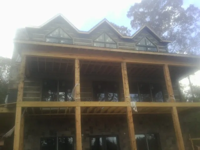 Dormers and porch framing on a large log home under construction — Roof Coating work by our crew in Erieville
