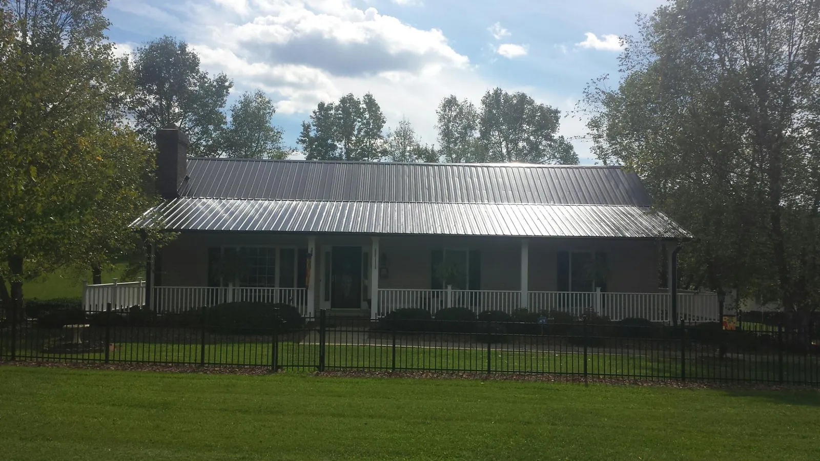 Gray metal roof on a brick ranch with a full width front porch — Gutter Guard Installation work by our crew in Erieville