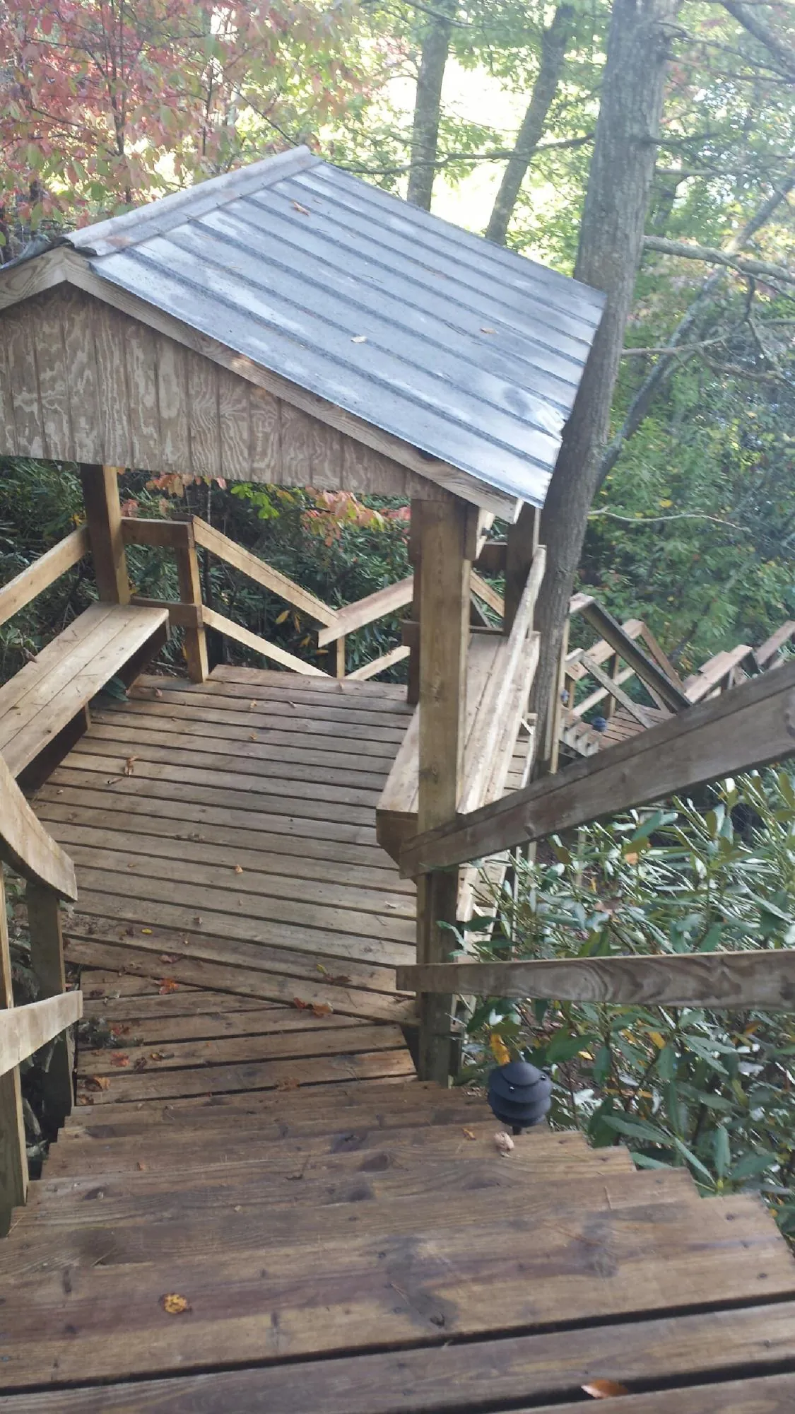Metal roofed shelter over wooden steps on a wooded walkway — Skylight Repair & Installation work by our crew in Erieville