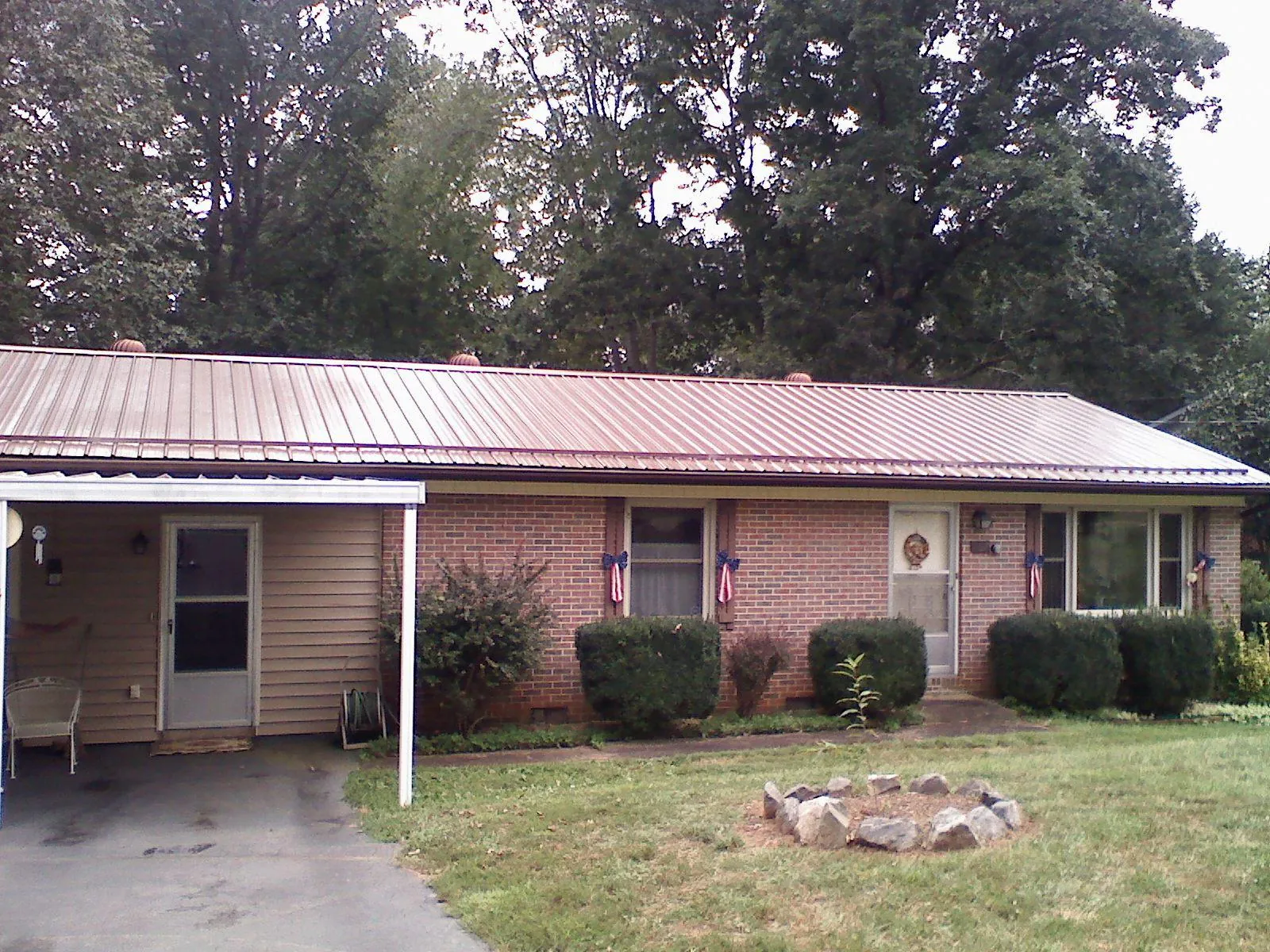 Bronze metal roof and carport on a brick ranch home — Roof Repair work by our crew in Erieville