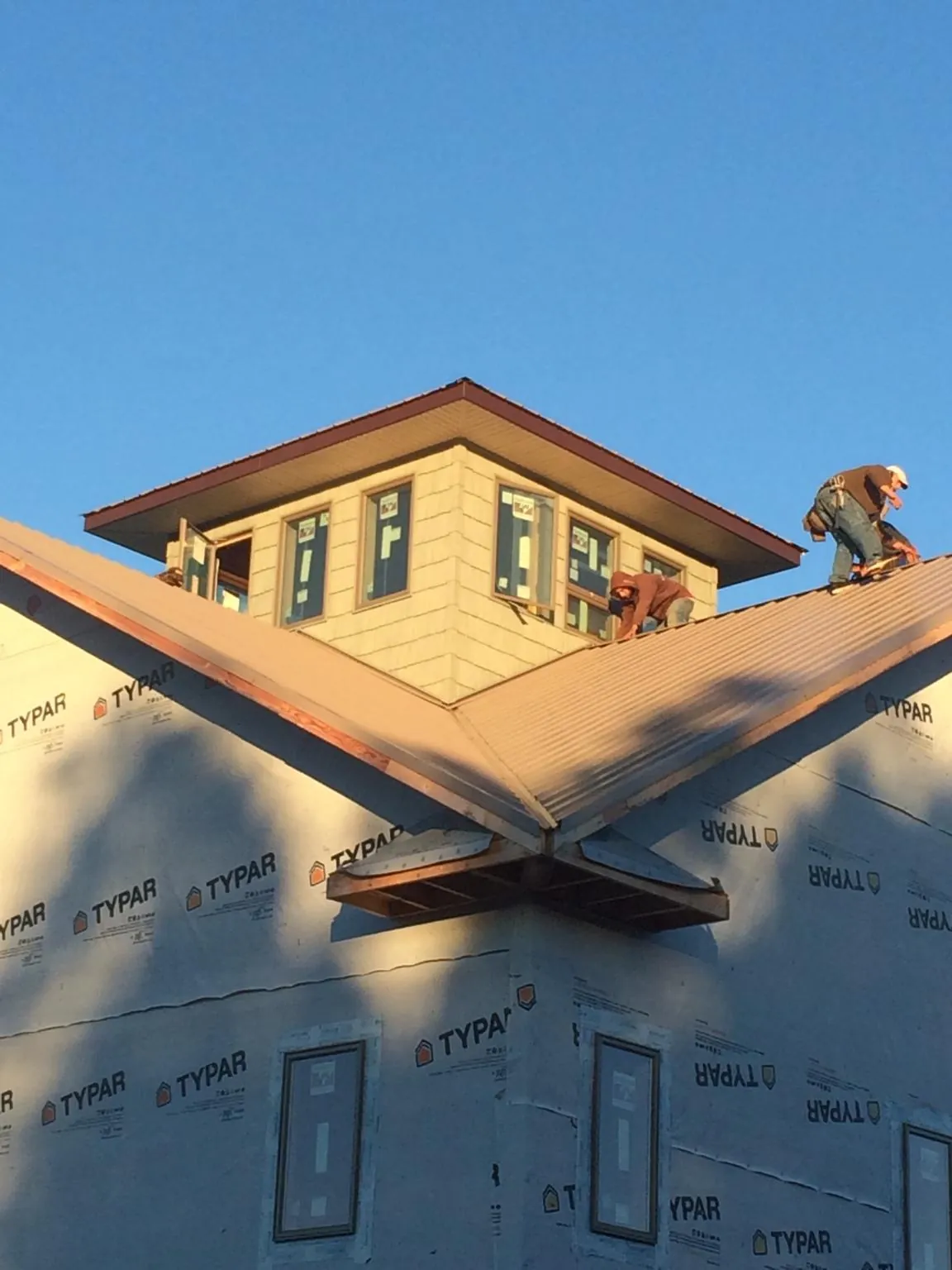 Roofers working around a rooftop cupola on a new metal roof at sunset — Roof Waterproofing in Erieville by Roofing Brothers